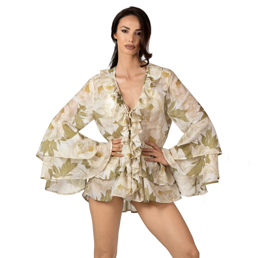 Woman wearing the FLEUR DE LUMIÈRE Short Tunic by BILEYA COUTURE, crafted from luxurious silk-cotton chiffon with a romantic white peony floral print, voluminous ruffle sleeves, and an airy designer resort wear silhouette.
