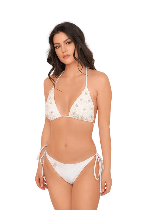 Woman wearing a white bikini with floral patterns on a plain background